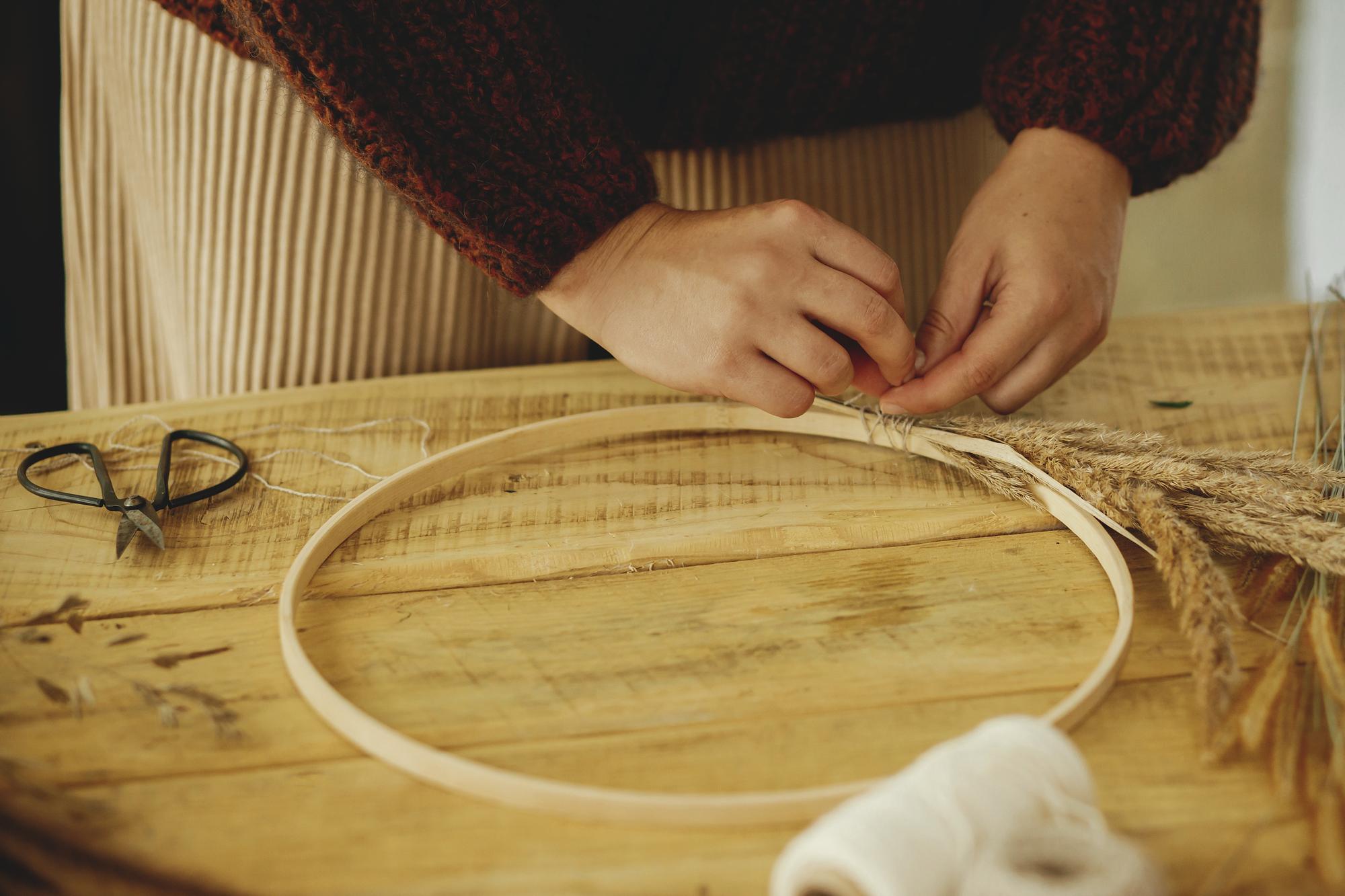 artisan embroiderer at a wooden table with threads and hoops